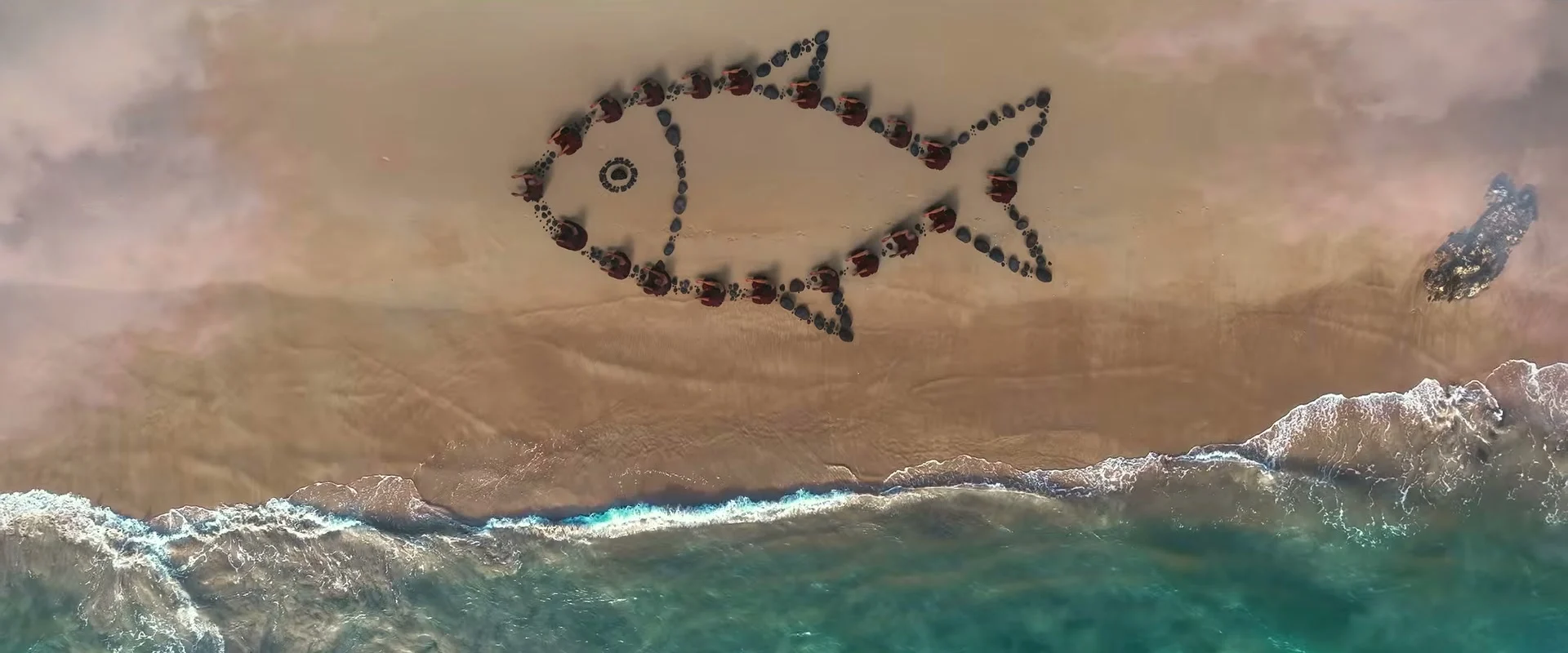 An illuminated fish outline on the shore